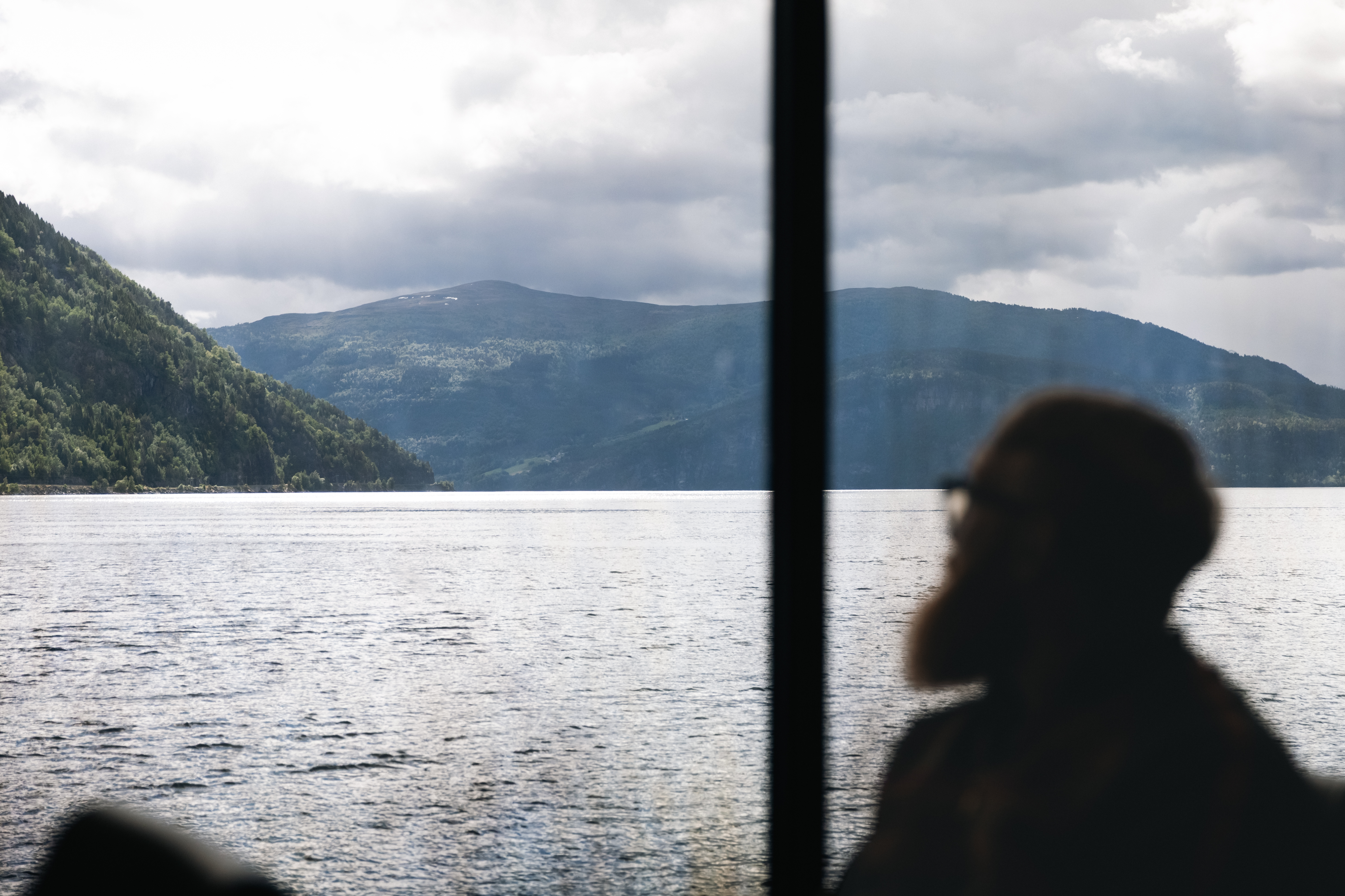 Passasjer ser ut over fjorden frå ferjesalongen.